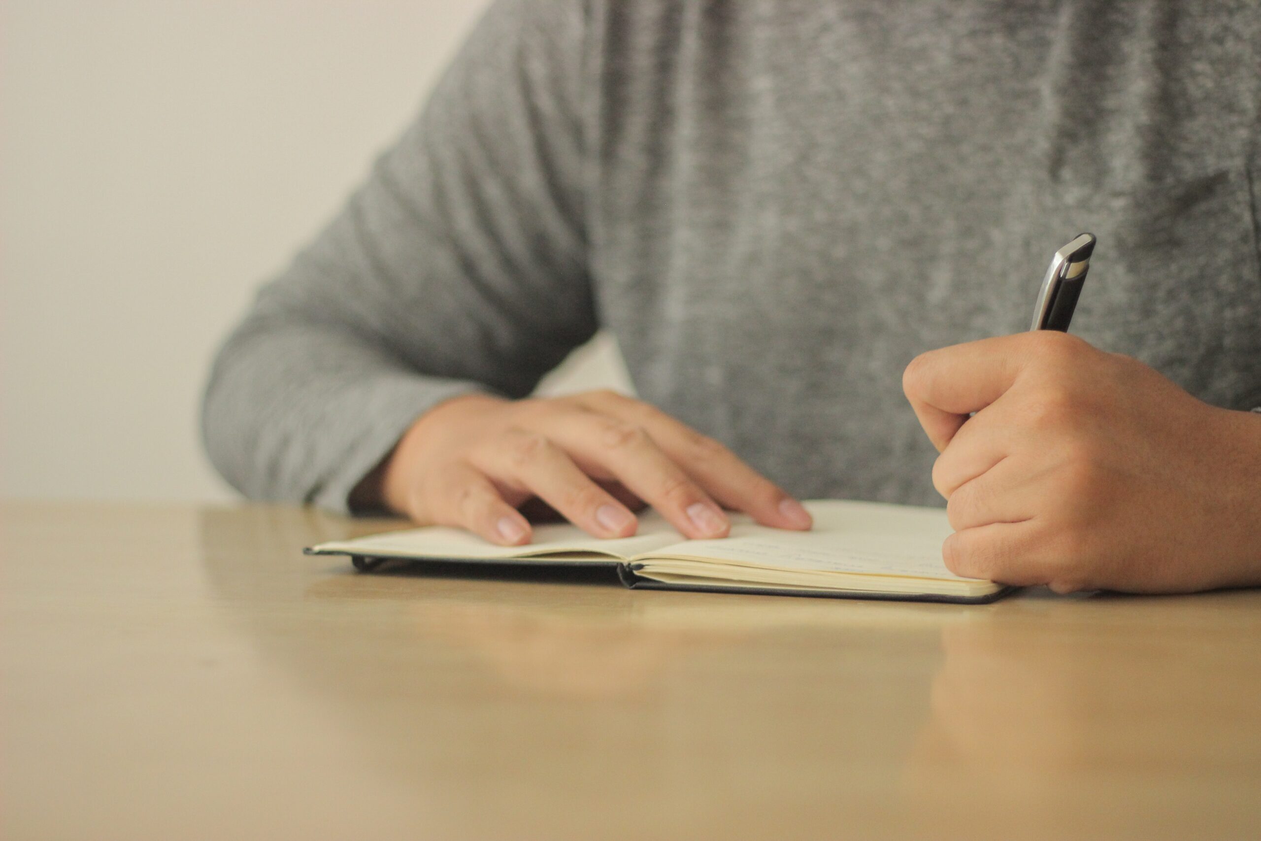 man writing on his notebook with a black pen